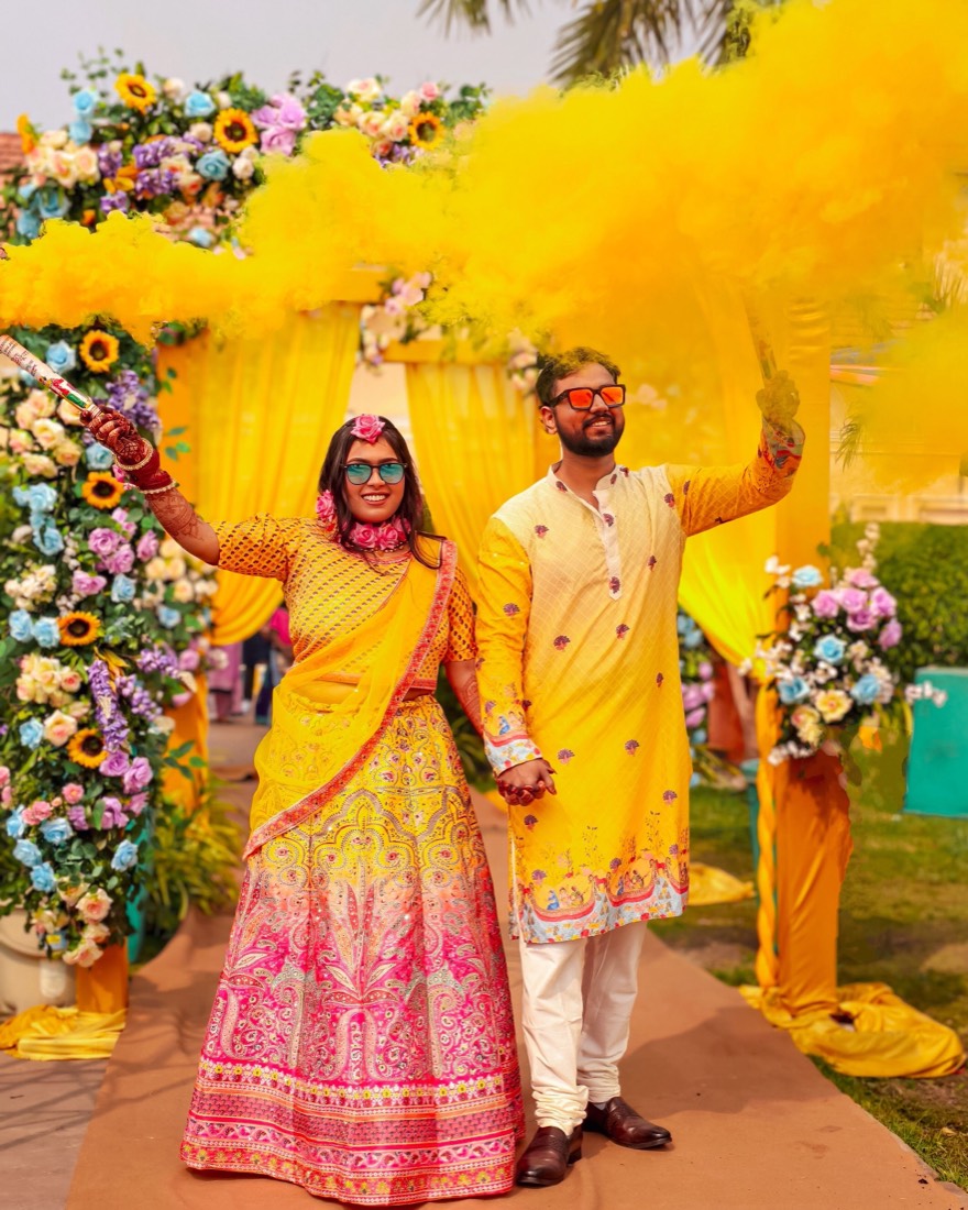 Couple portrait under a vibrant floral haldi arch styled by SGR Decorators